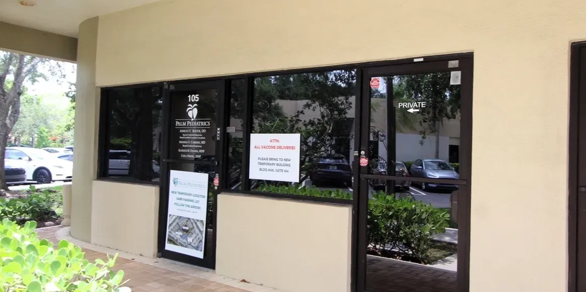 Storefront with multiple signs on glass doors.