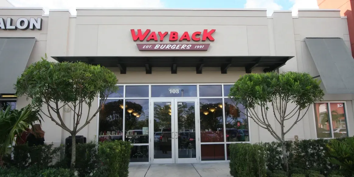 Wayback Burgers restaurant exterior with trees.