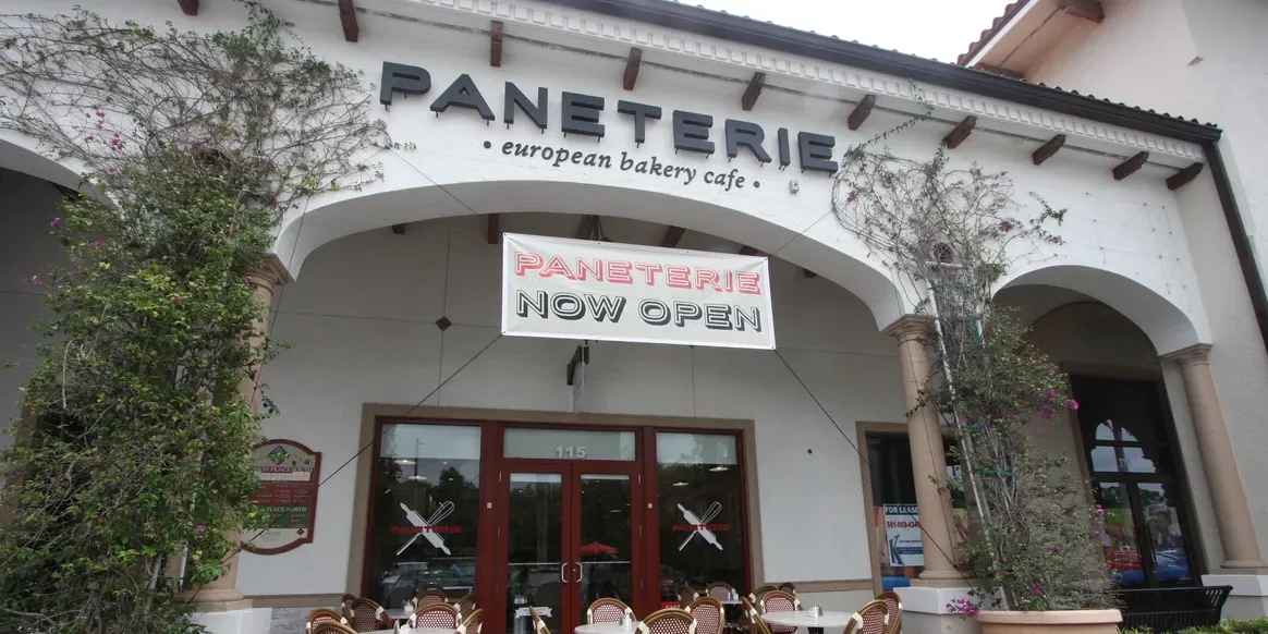 European bakery cafe exterior with "Now Open" sign.