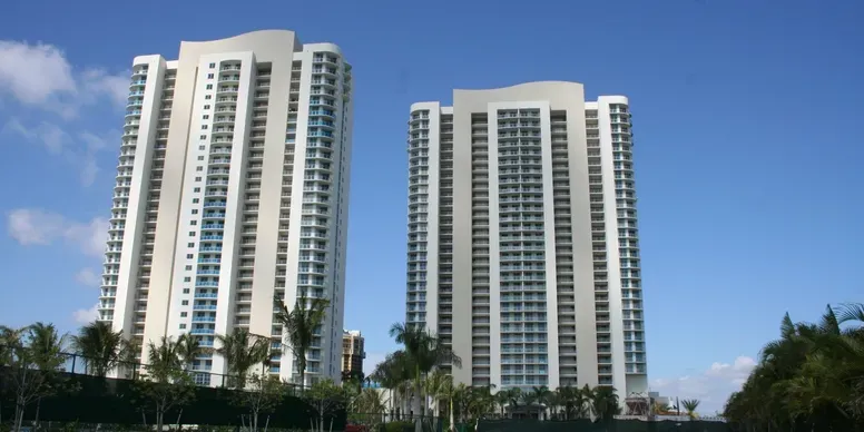 Two tall residential towers with palm trees.
