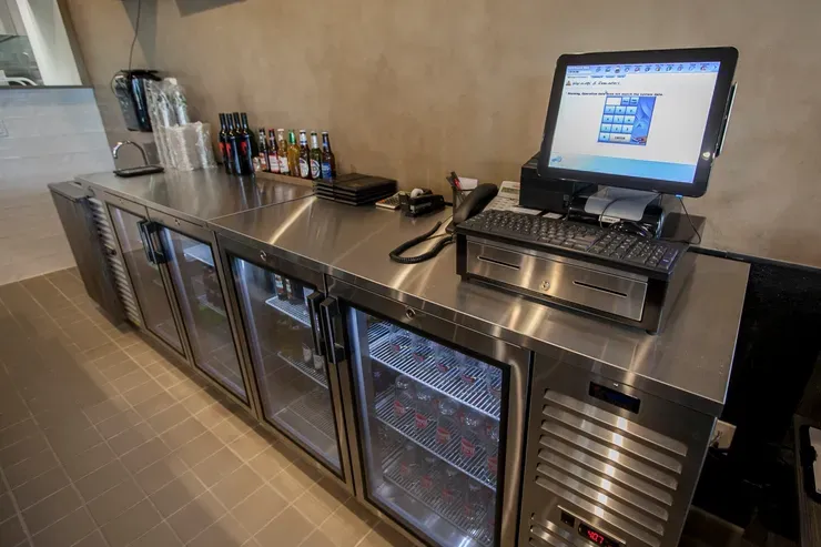 Bar counter with fridge and cash register.