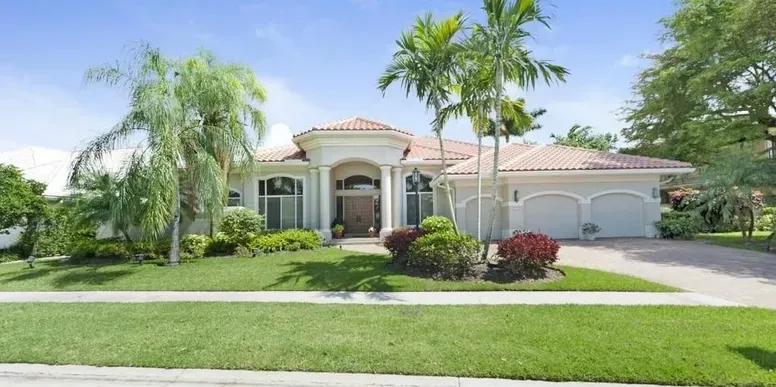 Elegant house with palm trees and lawn.